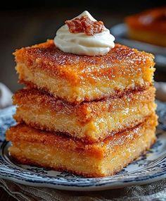 three pieces of cake sitting on top of a blue and white plate topped with whipped cream