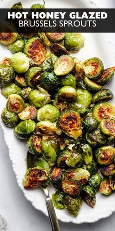 roasted brussel sprouts on a white plate with a serving knife and fork