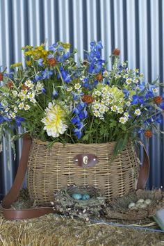 a basket filled with flowers sitting on top of hay