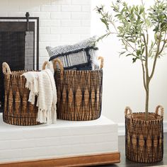 two woven baskets sitting on top of a white mantle next to a potted plant