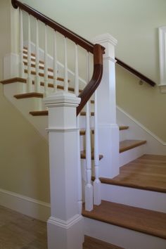 a white staircase with wooden handrails and banister rails in a home's entryway