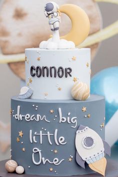 a birthday cake with an astronaut theme on it's top and the words, dream big little one