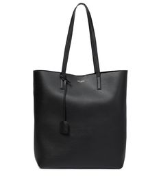 The Saint Laurent woman exudes Parisian sophistication as she saunters along city streetsâ" usually with the Shopping tote thrown over one shoulder. Made from smooth calf leather, this spacious is subtly embossed with logo detailing and features an encased monogram tag. The black colorway will will slot seamlessly into your everyday rotations. | Saint Laurent Shopping Large leather tote Saint Laurent Tote, Black Leather Tote Bag, Large Leather Tote, North South, Saint Laurent Bag, Leather Shops, Shopping Tote Bag, Shopper Bag, Shopping Tote