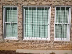 two windows with bars on them in front of a brick building