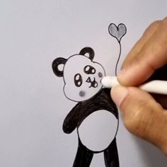 someone is drawing a panda bear on the paper with a white marker and it looks like he's holding a heart