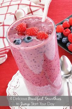 a smoothie with berries and blueberries in it on a plate next to a bowl of raspberries