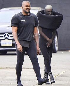 two men walking down the street with one wearing a black shirt and leggings