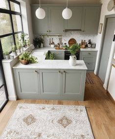 a kitchen filled with lots of green cabinets and white counter tops next to a window