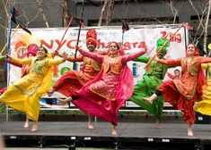 some people are dancing on stage with their arms in the air and holding onto sticks