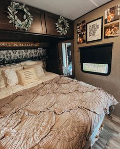 a bed in a bedroom with pictures on the wall above it, and a window