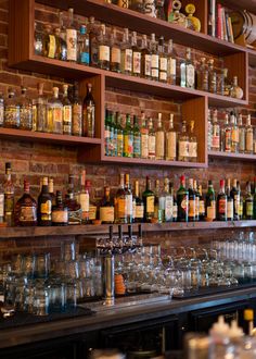 many bottles and glasses are lined up on the bar