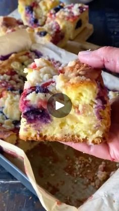 someone is holding up a piece of cake with blueberries and crumbled toppings