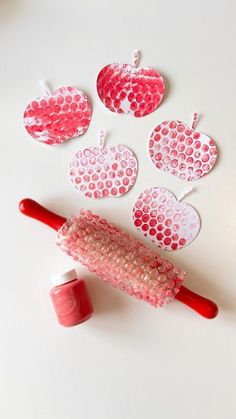 paper hearts are cut out and placed next to a crafting roller with glue on it