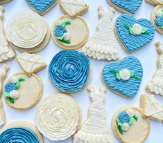 decorated wedding cookies arranged in rows on white tablecloth with blue and white decorations around them