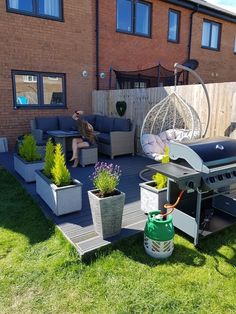 an outdoor patio area with potted plants and bbq grill in the back yard