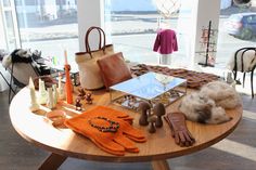 a table with many items on it in front of a large window, including gloves and purses