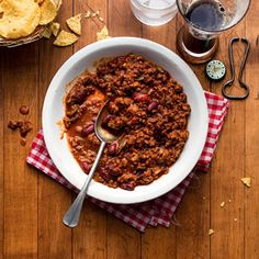 a bowl of chili and chips on a wooden table