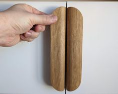 a person's hand reaching for the door handle on a cabinet