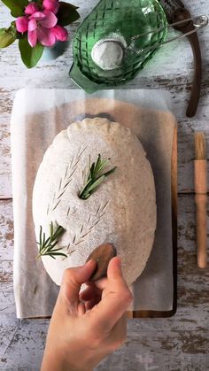 a person is making a pizza on a cutting board with flowers and other items around it