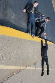 two men are standing on the edge of a wall