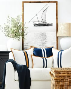 a living room with a white couch and blue striped pillows on the back of it