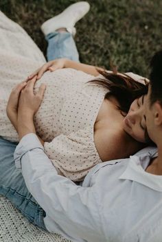 a man and woman are laying on the grass with their heads close to each other