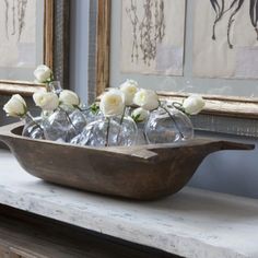 white roses are in glass vases on a wooden tray next to an antique mirror