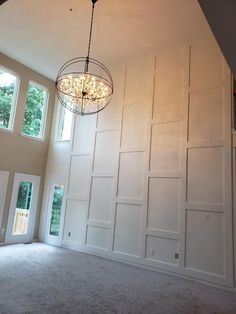 a chandelier hangs from the ceiling in an empty room with white paneling