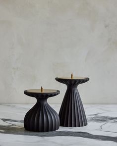 two black candle holders sitting on top of a marble table