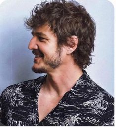 a close up of a person wearing a black and white shirt with his hair blowing in the wind