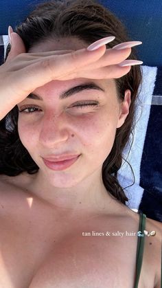 a close up of a person laying in a chair with their hands on her head