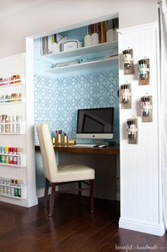 a room with a desk, computer and shelves on the wall