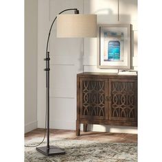 a lamp that is on top of a table next to a dresser and cabinet in a room