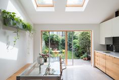 an open kitchen and dining room area with skylights above the counter top, along with glass doors leading outside