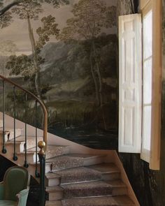 a staircase leading up to a painting on the wall next to a table and chairs