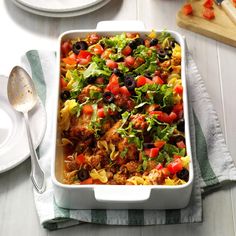 a white casserole dish filled with meat and veggies on a table