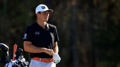 a man in black shirt and white hat holding a golf club