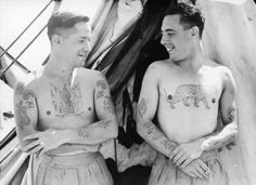 two men with tattoos standing next to each other