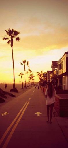 a woman walking down the street at sunset