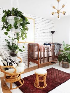 a baby's room with a crib, rocking chair and potted plants