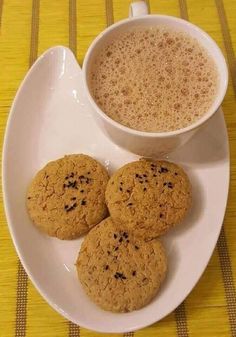 three cookies on a plate next to a cup of coffee