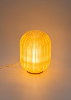 a yellow lamp sitting on top of a white table next to a light brown wall