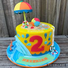 a birthday cake with an umbrella and the number two on it is decorated in bright colors