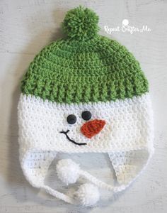 a crocheted hat with a snowman face on the front and green top