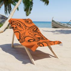 an orange and black beach chair sitting on top of a sandy beach