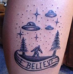 a tattoo on the leg of a person with trees and an alien flying over them