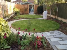 a garden with flowers in the middle and a stone path leading to a small building