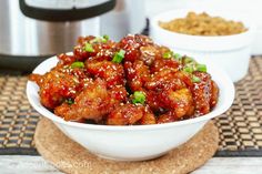 a white bowl filled with chicken and green onions next to an instant pressure cooker