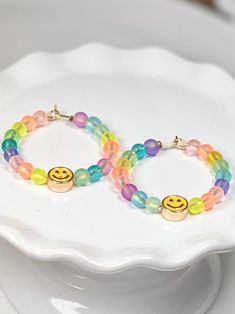 If what you wear affects how you feel, then these happy little earrings are sure to bring a smile to your face! A hoop full of 4 mm glass beads frame a single smiley-face enameled metal bead. She measures about 1 1/2 inches from the top of the hoop, to the bottom of the smiley face. Playful Multicolor Smiley Face Jewelry, Adjustable Fun Hoop Earrings Nickel Free, Adjustable Fun Nickel-free Hoop Earrings, Fun Adjustable Nickel-free Hoop Earrings, Fun Rainbow Hoop Earrings For Gift, Fun Rainbow Hoop Earrings As Gift, Playful Smiley Face Jewelry For Everyday, Hypoallergenic Round Fun Jewelry, Fun Summer Jewelry With Smiley Face