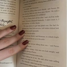 a woman's hand is holding an open book with writing on it and the pages are red